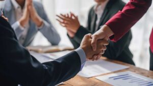 professionals in suits shaking hands in celebration of closing a deal