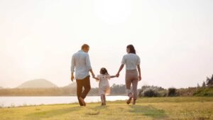 A child holds hand with their parents, one on either site, as they walk together